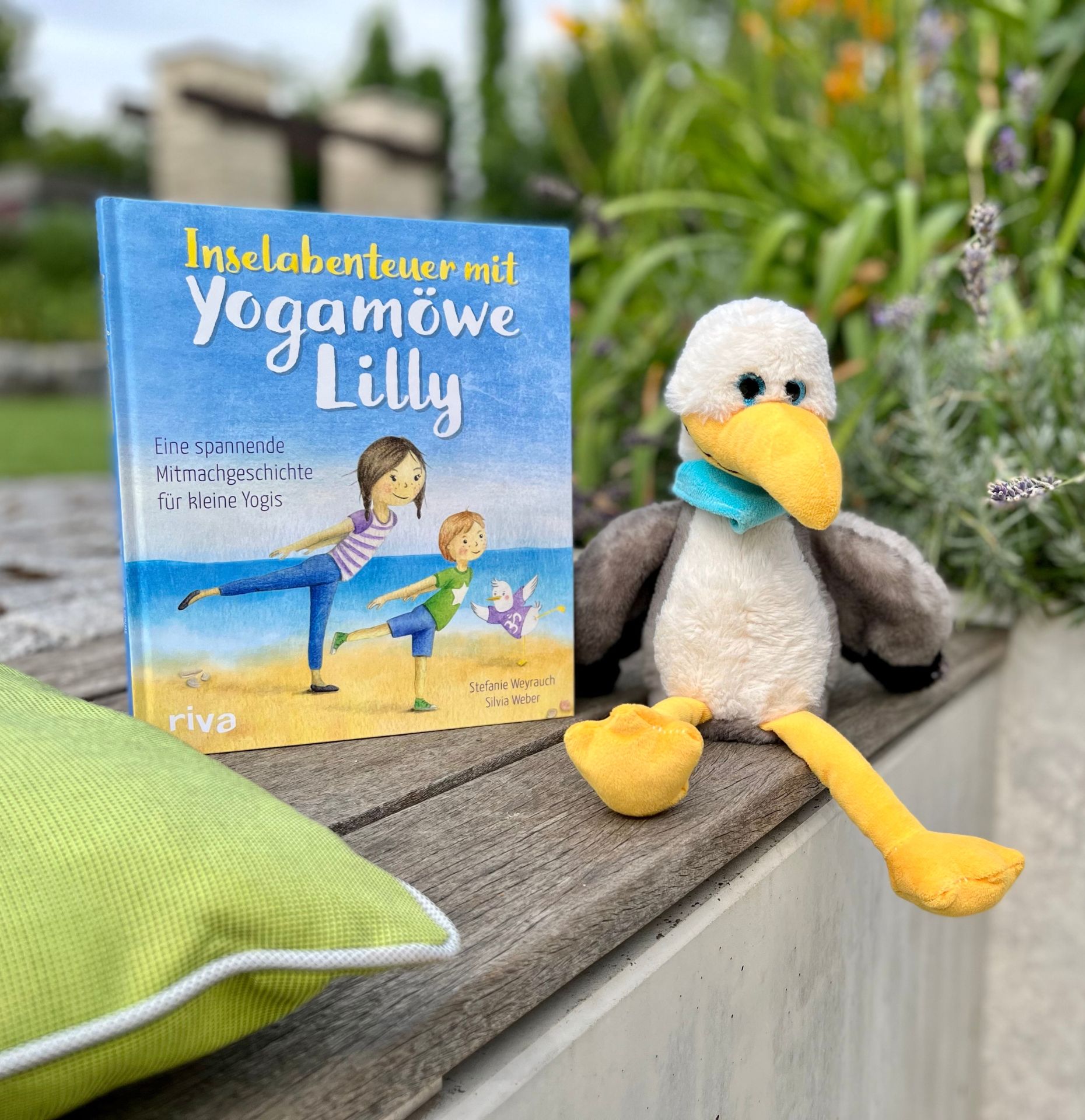 Bild des Kinderyogabuches 'Inselabenteuer mit Yogamöwe Lilly' neben einer Stofftiermöwe